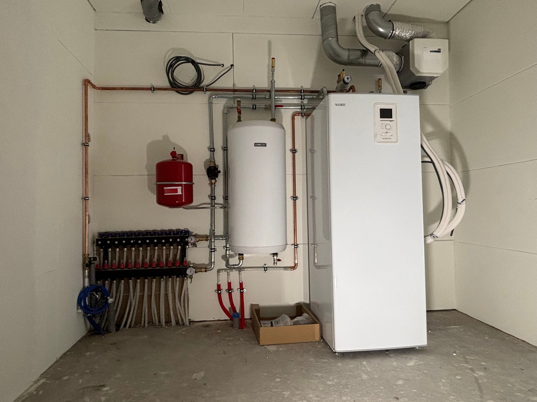 Technische ruimte met warmtepomp, boilervat, verdeler en leidingwerk